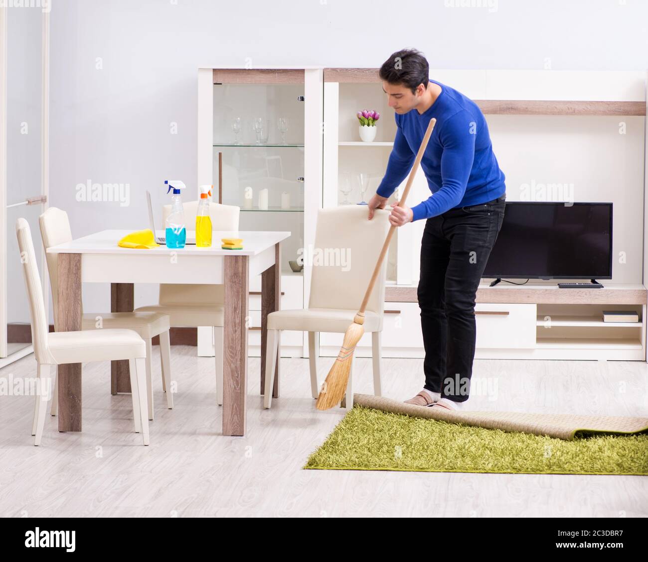 Young man cleaning floor with broom Stock Photo Alamy