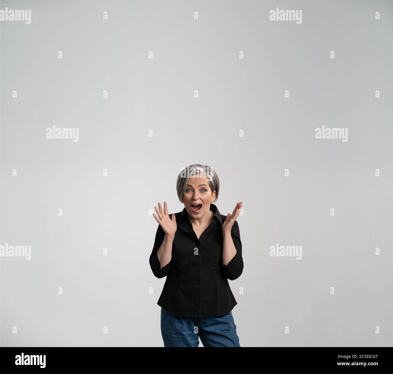 Surprised mature woman with opened mouth and palms. Positively shocked Caucasian lady in black shirt. Advertisement concept. Amazement concept. Square Stock Photo