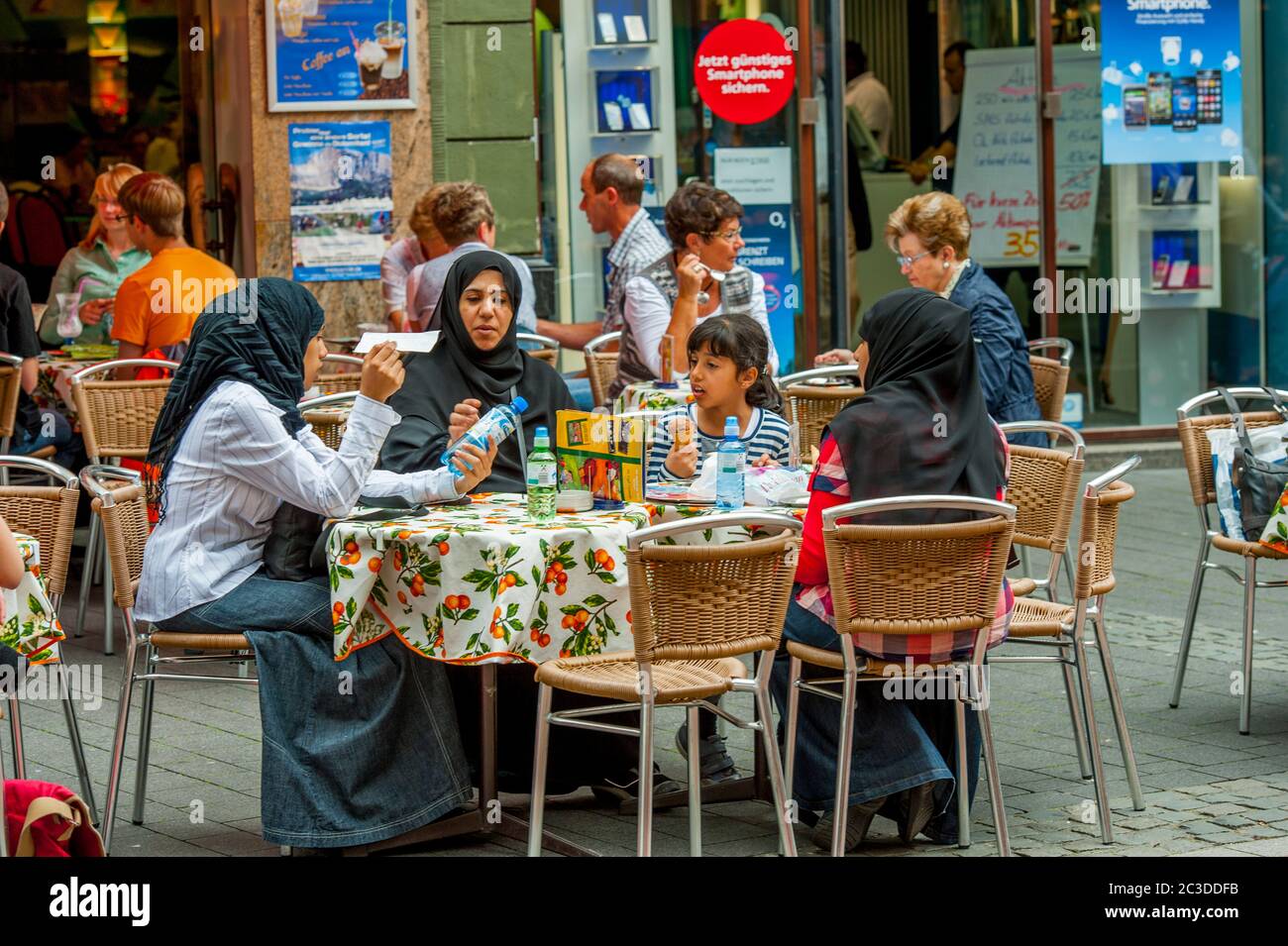 A Muslim family is having water and ice-cream in a sidewalk cafe in Bonn, Germany. Stock Photo