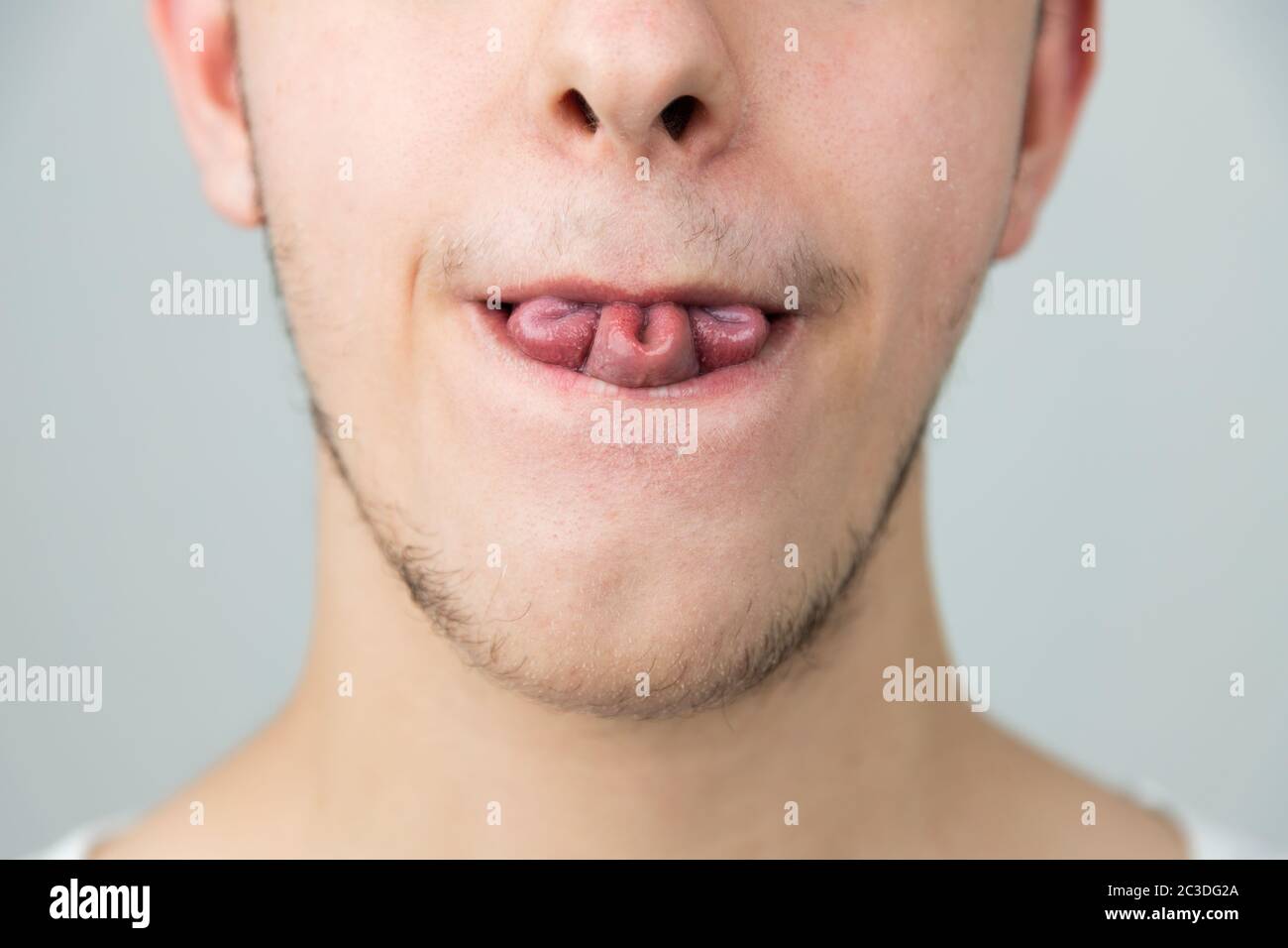 Close up of a young man, folding his tongue in a rare tri fold, clover leaf shape. Strange genetic ability. White Caucasian male on white background Stock Photo