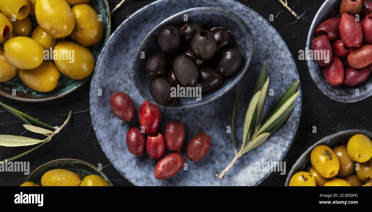 Olives overhead panorama. An assortment of green, black and red olives, shot from the top on a dark table Stock Photo