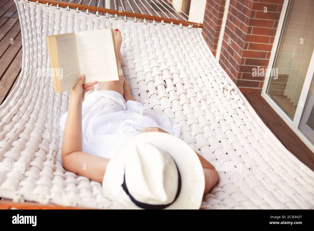 Woman lying in hammock and reading book Stock Photo - Alamy