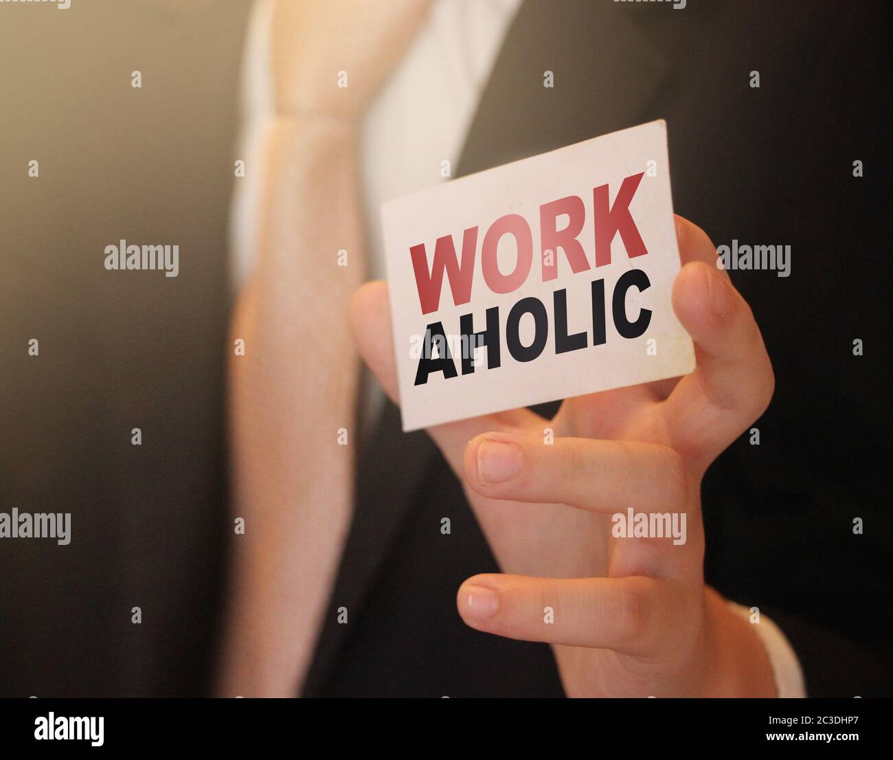 Workaholic word on a card in hand of businessman. Devoted to business or career concept Stock Photo