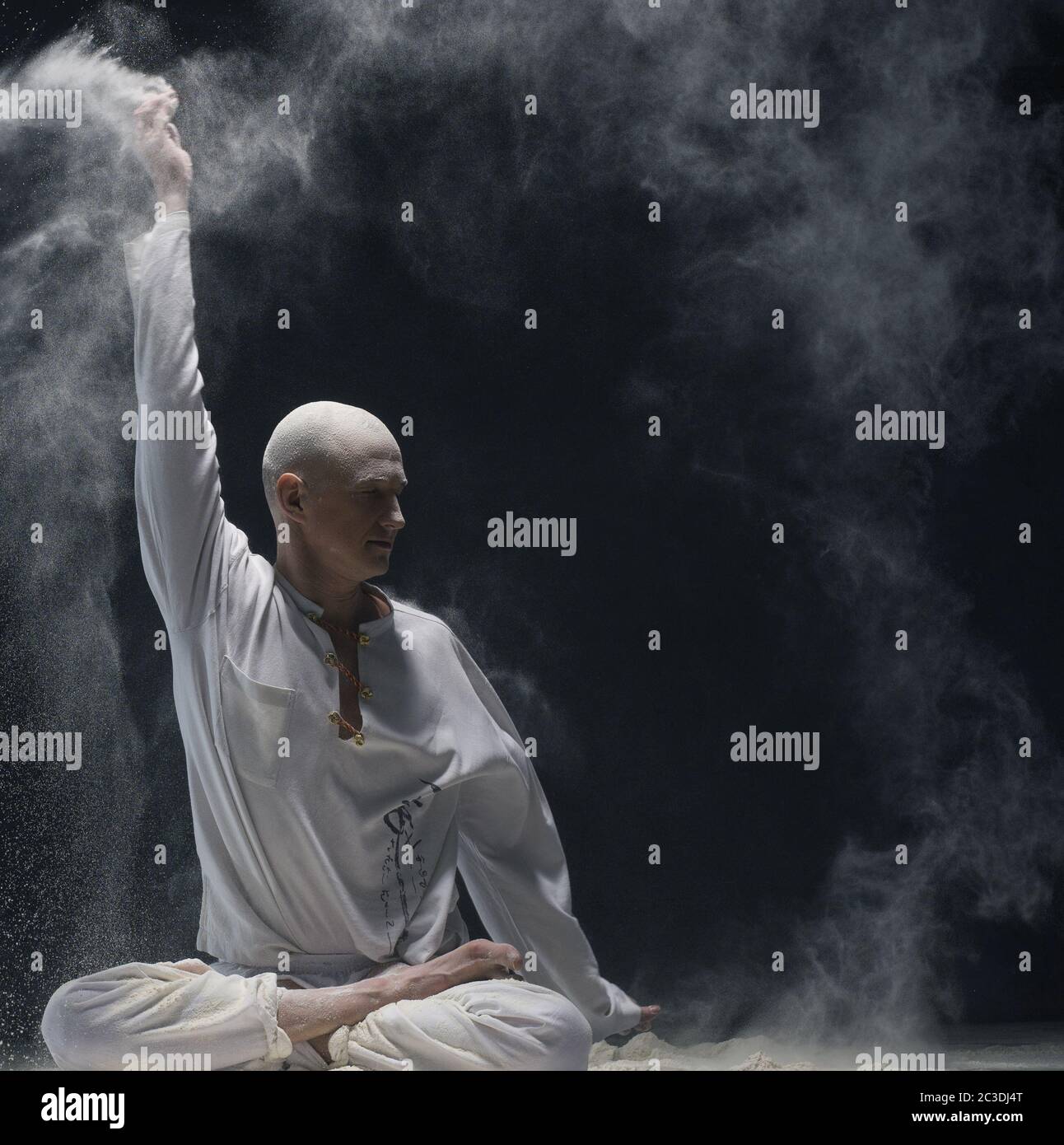 Man doing yoga in white dust cloud - concept of energy Stock Photo