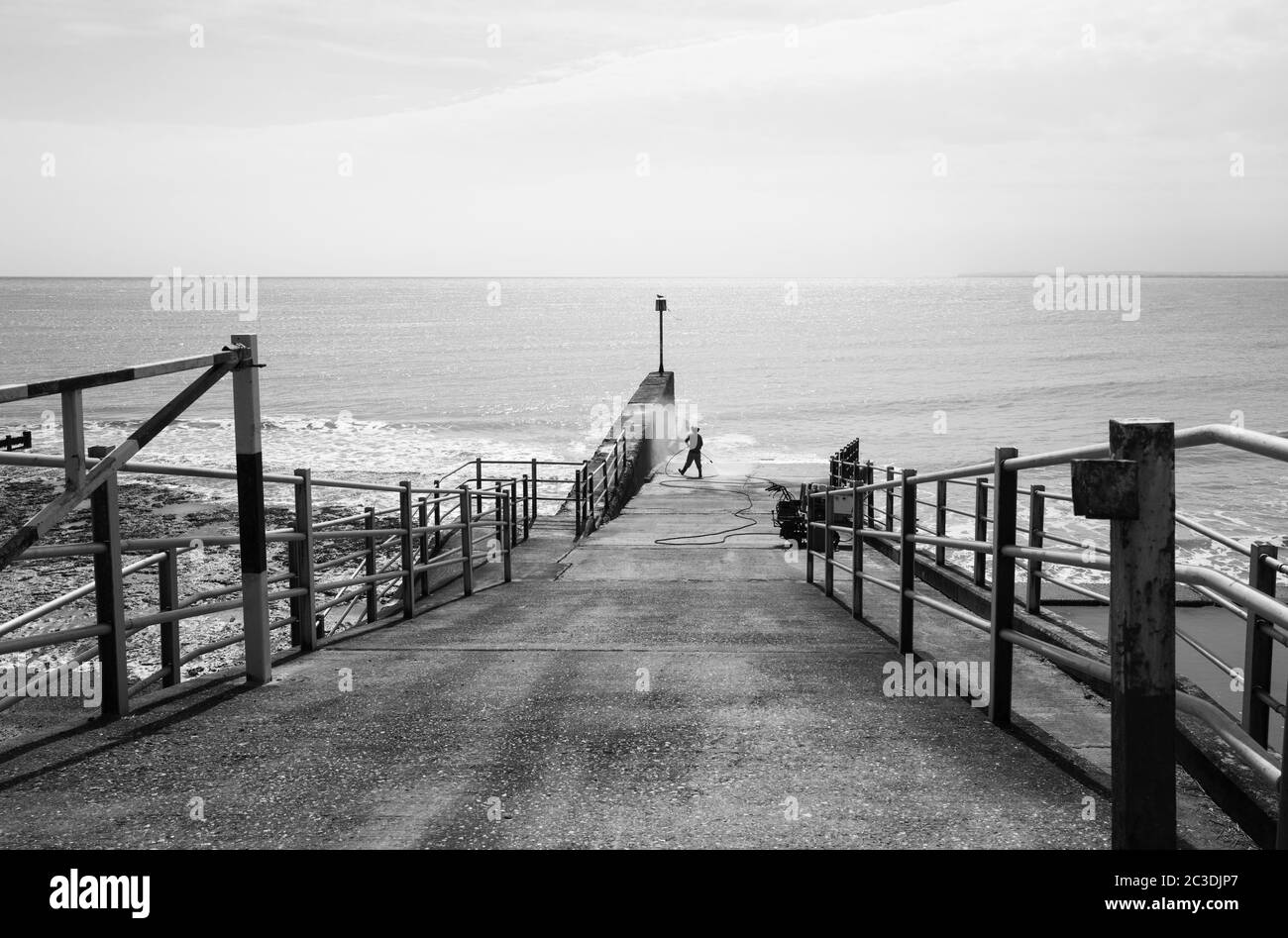 A man jet washes a jetty on the sea front on the west cliff in Ramsgate Stock Photo