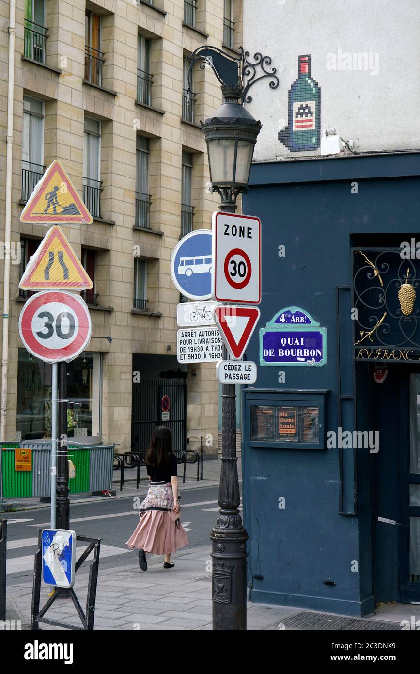 A woman walking at a Parisian street corner in 4th arrondissement with traffic and speed limit warning signs in foreground.Paris.France Stock Photo