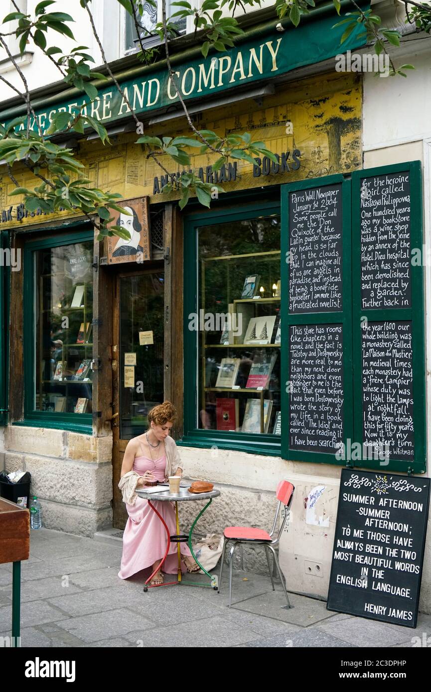 Woman in a pink dress is reading a book outside of Shakespeare and Company bookstore.Paris.France Stock Photo