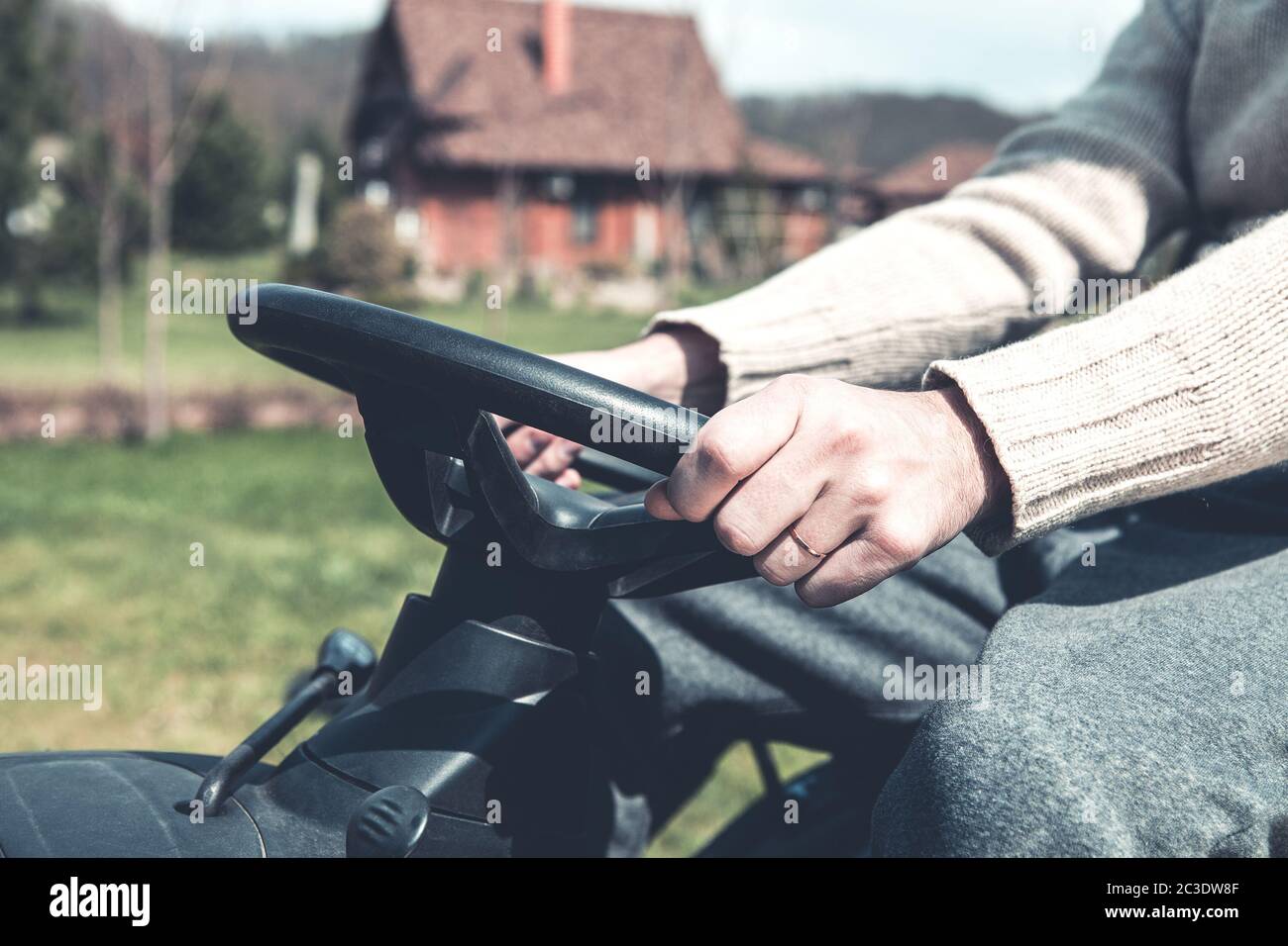 Man working while riding lawn mower on yard Stock Photo