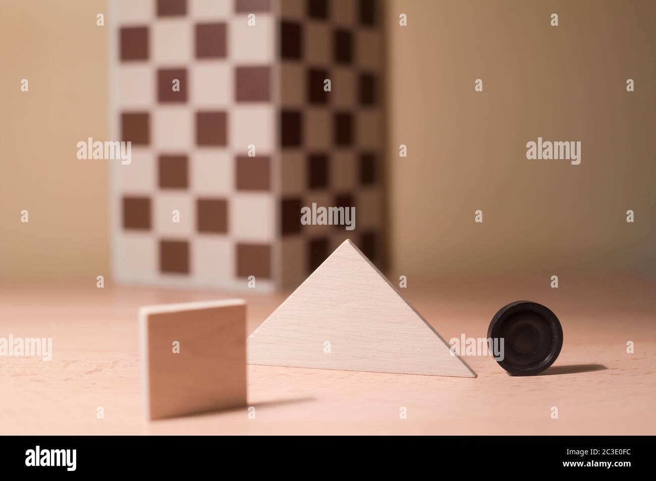 Composition of various objects - square, triangle, chessboard, round - on wooden desk. Shallow depth of field and cream tint. Stock Photo