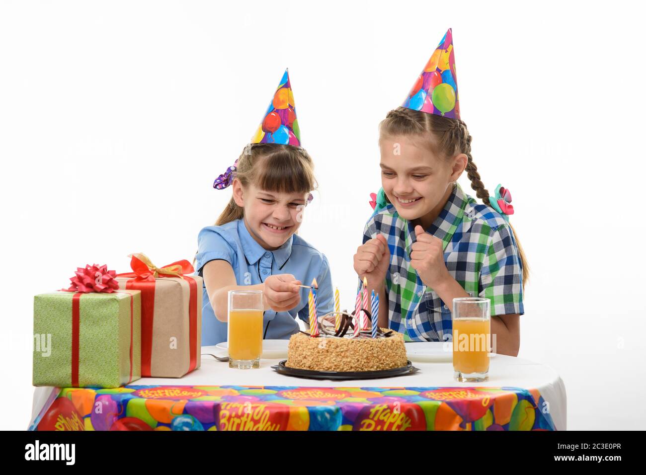 Children independently light candles on a pie at the festive table Stock Photo