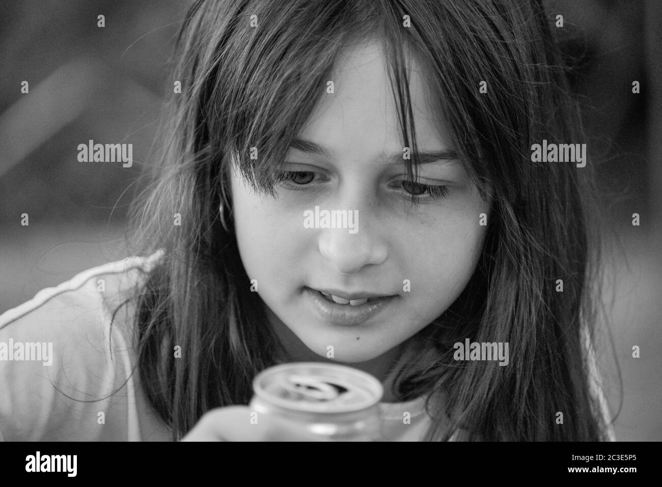 Young girl drink water. Teen girl drinks with an iron can. A 9-year-old girl holds a drink in her hands. Stock Photo