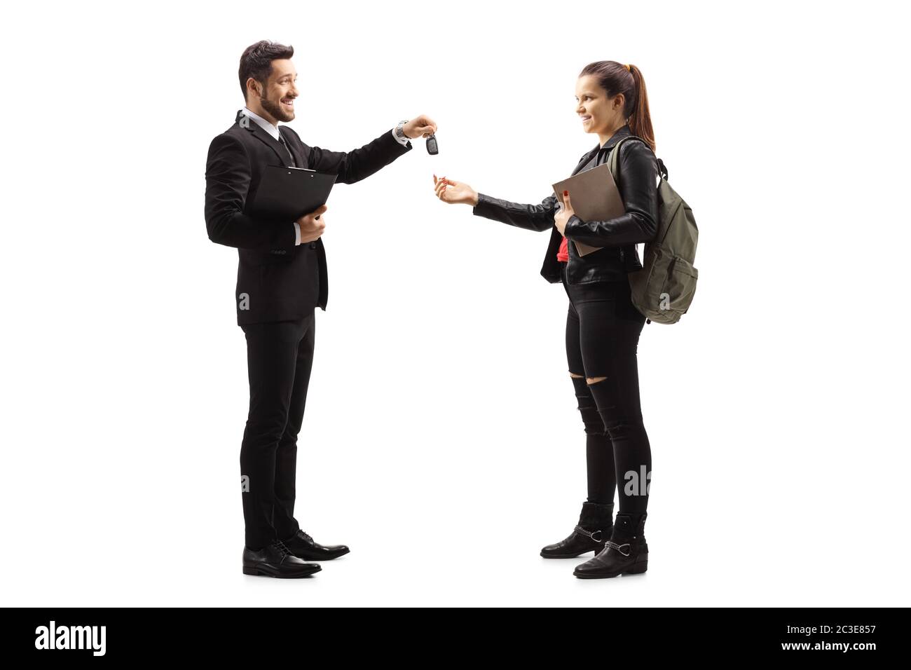 Full length profile shot of a salesman giving car keys to a young female isolated on white background Stock Photo