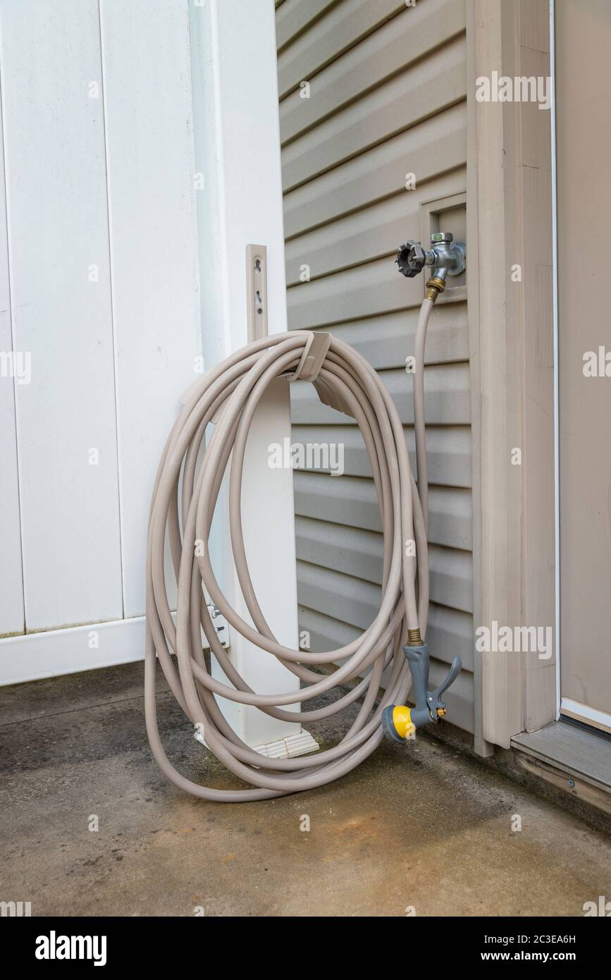 Vertical shot of a rolled up and hung patio garden hose. Stock Photo