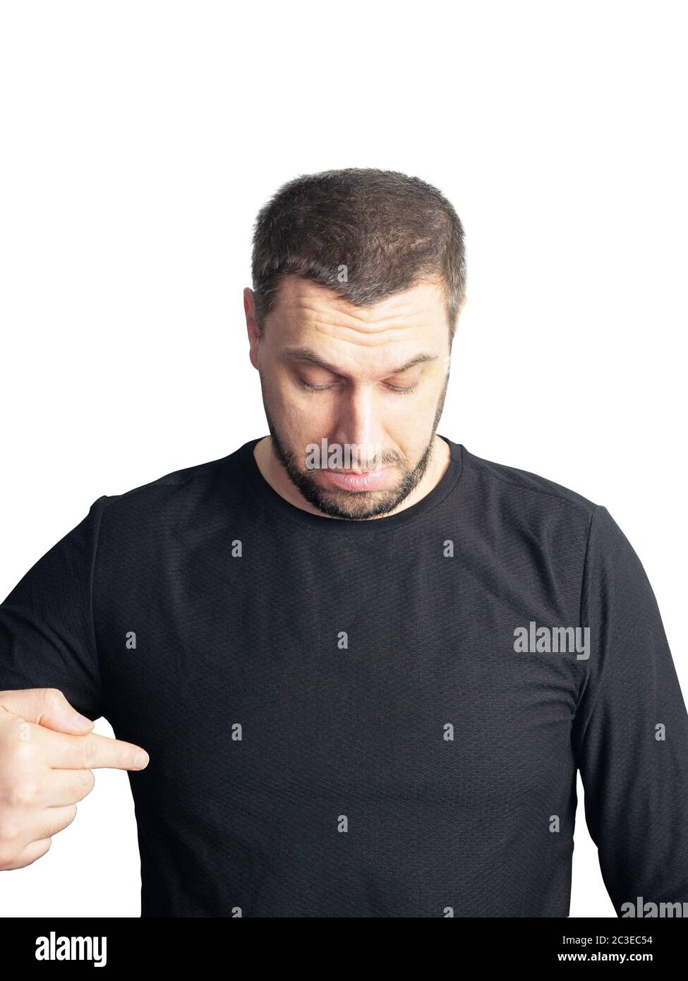 A bearded man in a black sweater looks down and points a finger on a white background Stock Photo