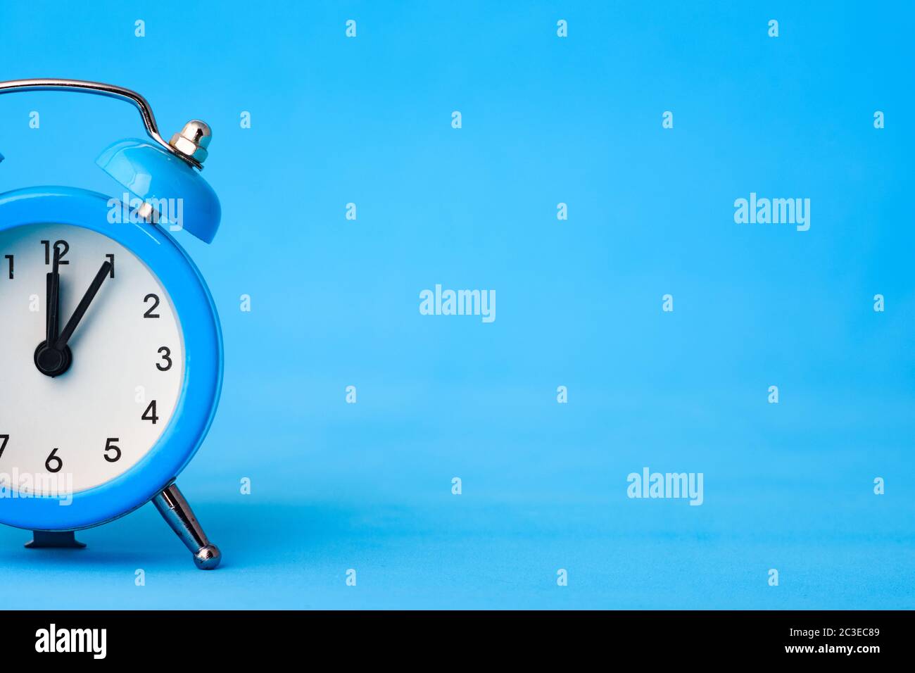 Part of the alarm clock on the left, on the right is an empty place, blue background Stock Photo