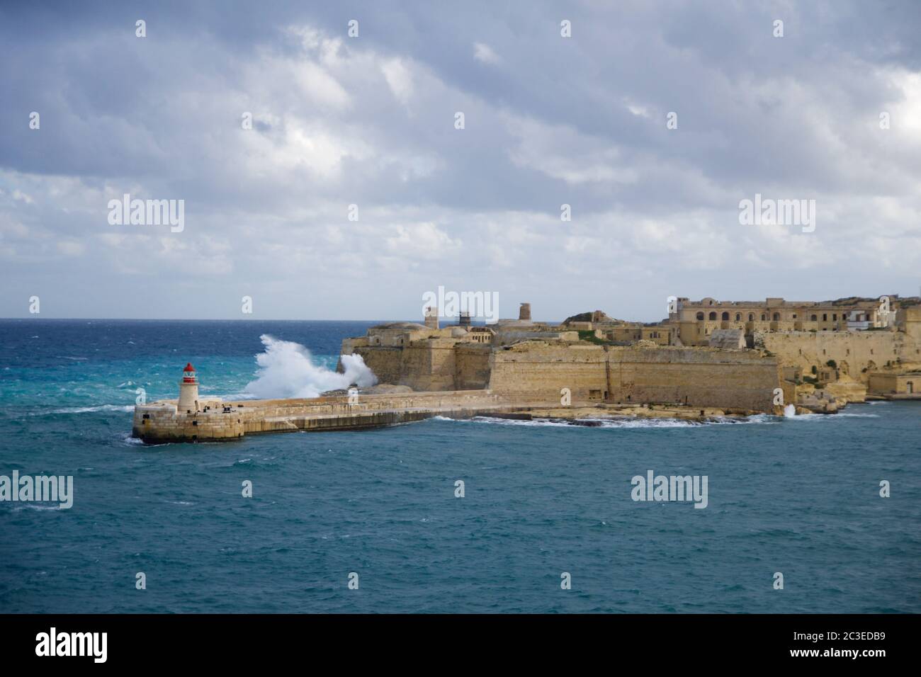 VALLETTA, MALTA - DEC 31st, 2019: View from Fort St Elmo on to the Ricasoli Grand Harbour East Breakwater and red lighthouse during strong waves Stock Photo