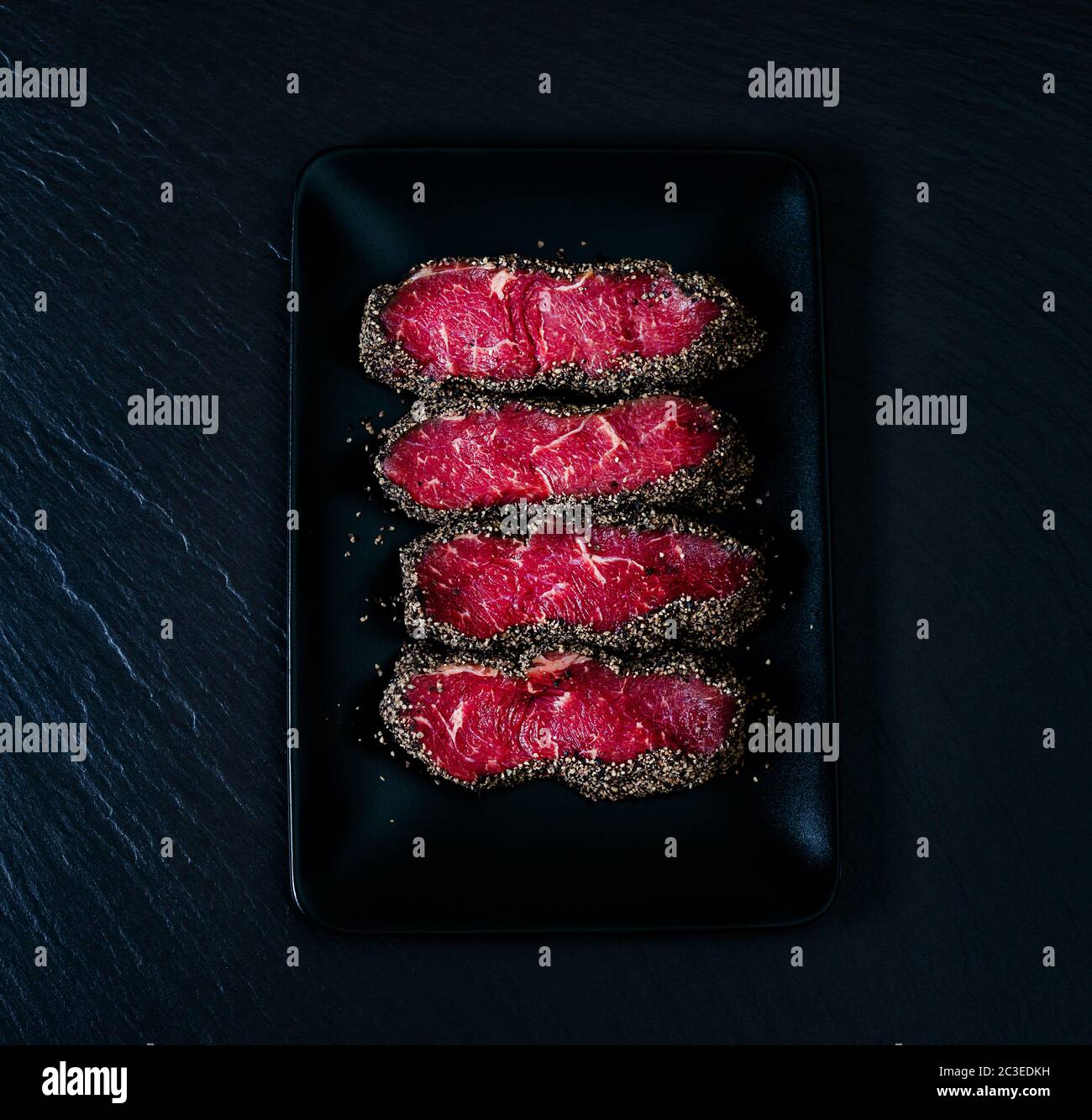 Top view on pepper steaks on black stone plate Stock Photo