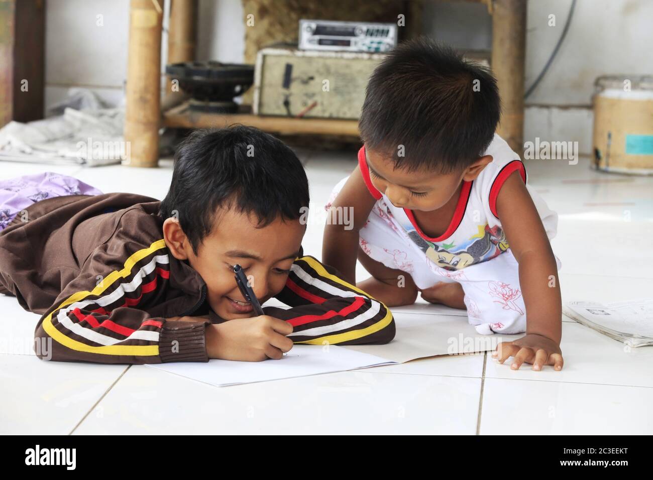 Children of an Indonesian artist paint while sitting on the floor. Bali Stock Photo