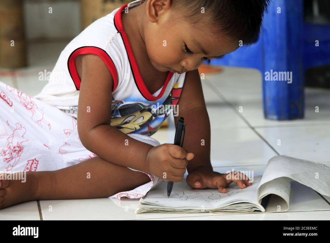 The child of the Indonesian artist draw sitting on the floor. Bali Stock Photo