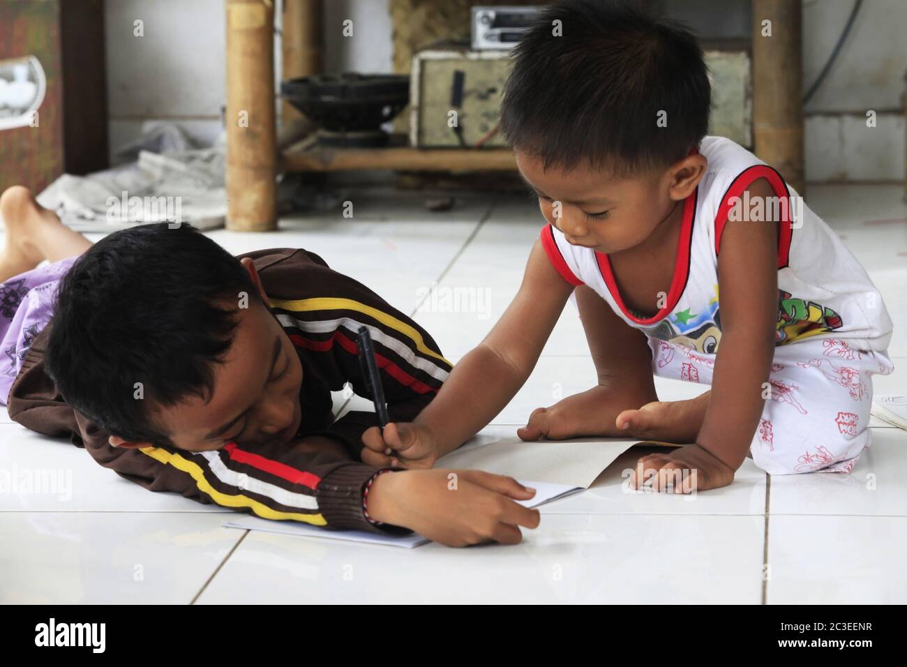 Children of an Indonesian artist paint while sitting on the floor. Bali is famous for talented artis Stock Photo