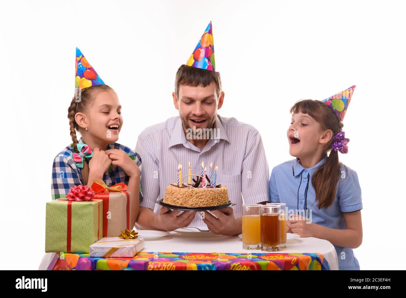 Dad and two daughters took a little more air to blow out the candles on the holiday cake Stock Photo