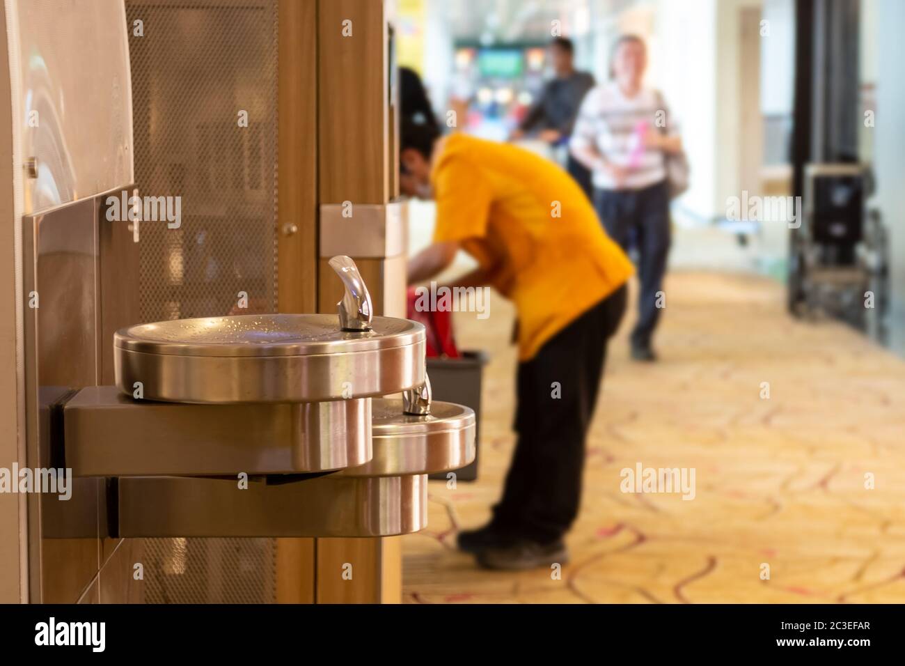 Stainless steel drinking fountains in airport. Men drink water on background Stock Photo Alamy