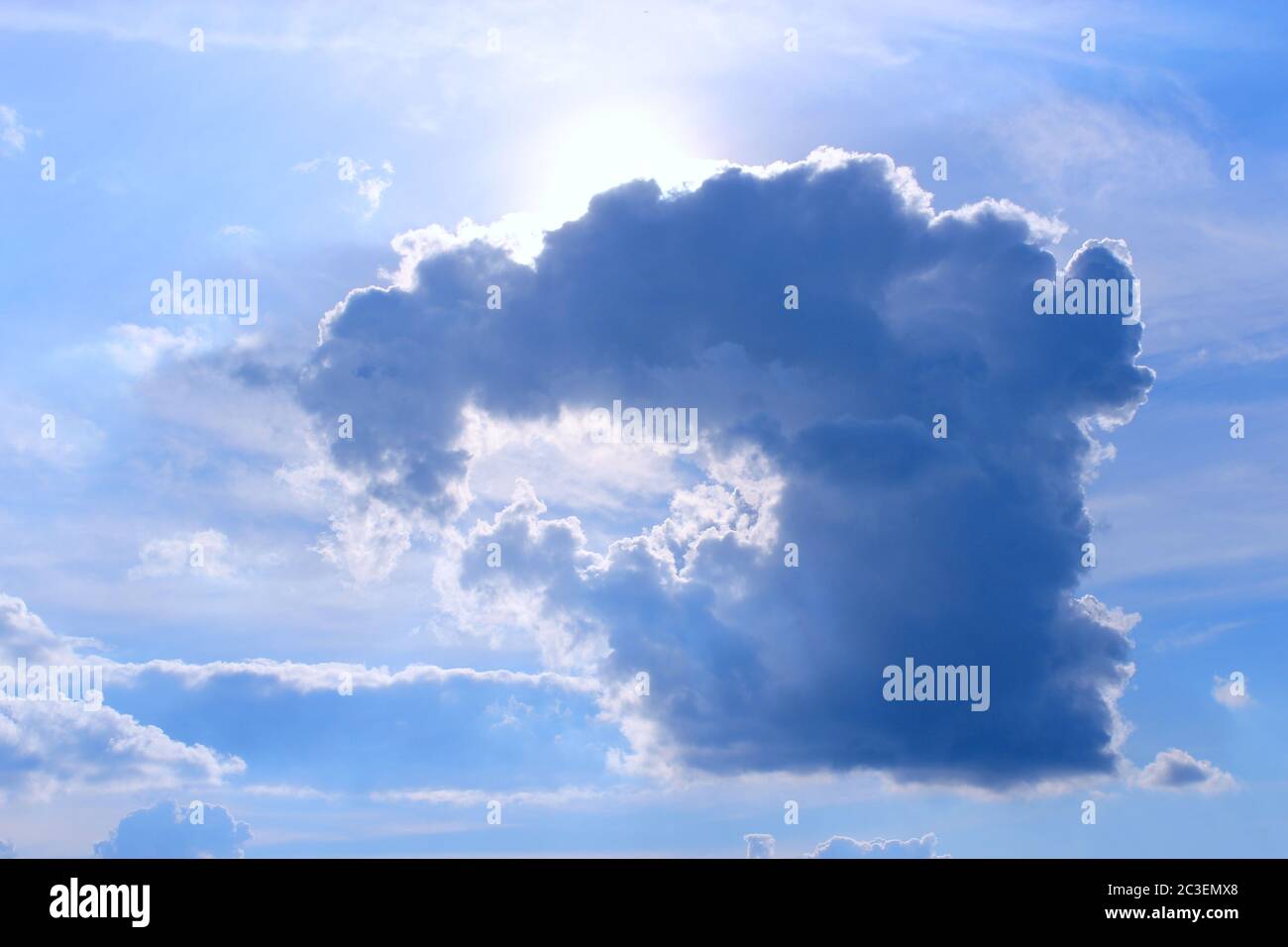 cloud with unusual shape and sunny beams. sun peeking out from behind dark cloud. Sun rays in cloudy Stock Photo