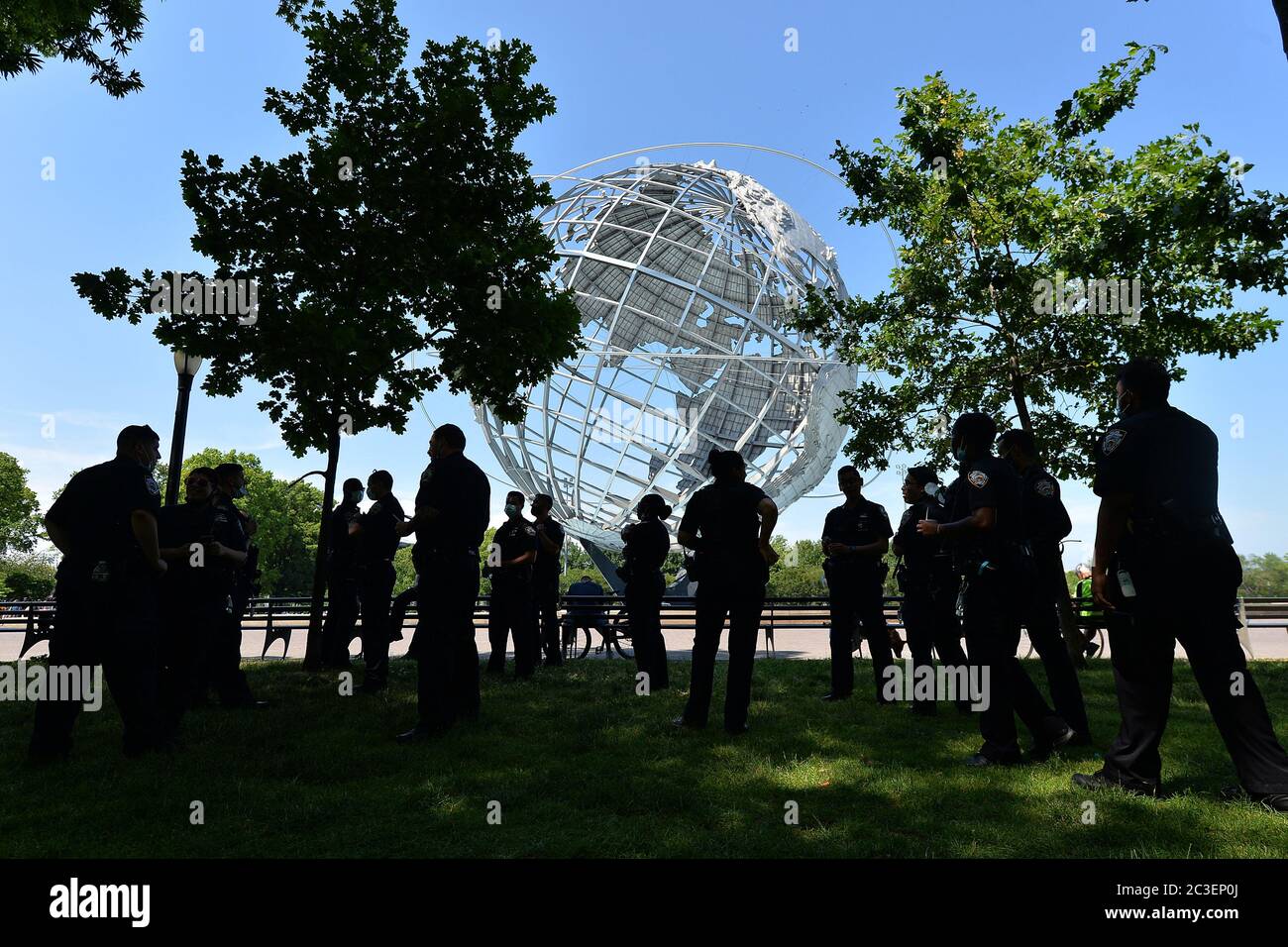 NYPD officers stand a few yards back in the shade at a peaceful celebration rally for Juneteenth takes place in front of hte Unisphere in Flushing Meadows-Corona Park in the borough of Queens, New York, June 19, 2020. Juneteenth is celebrated as a commemoration of the ending of slavery in the United States.   given on January 1, 1983, Credit: Sipa USA/Alamy Live News Stock Photo