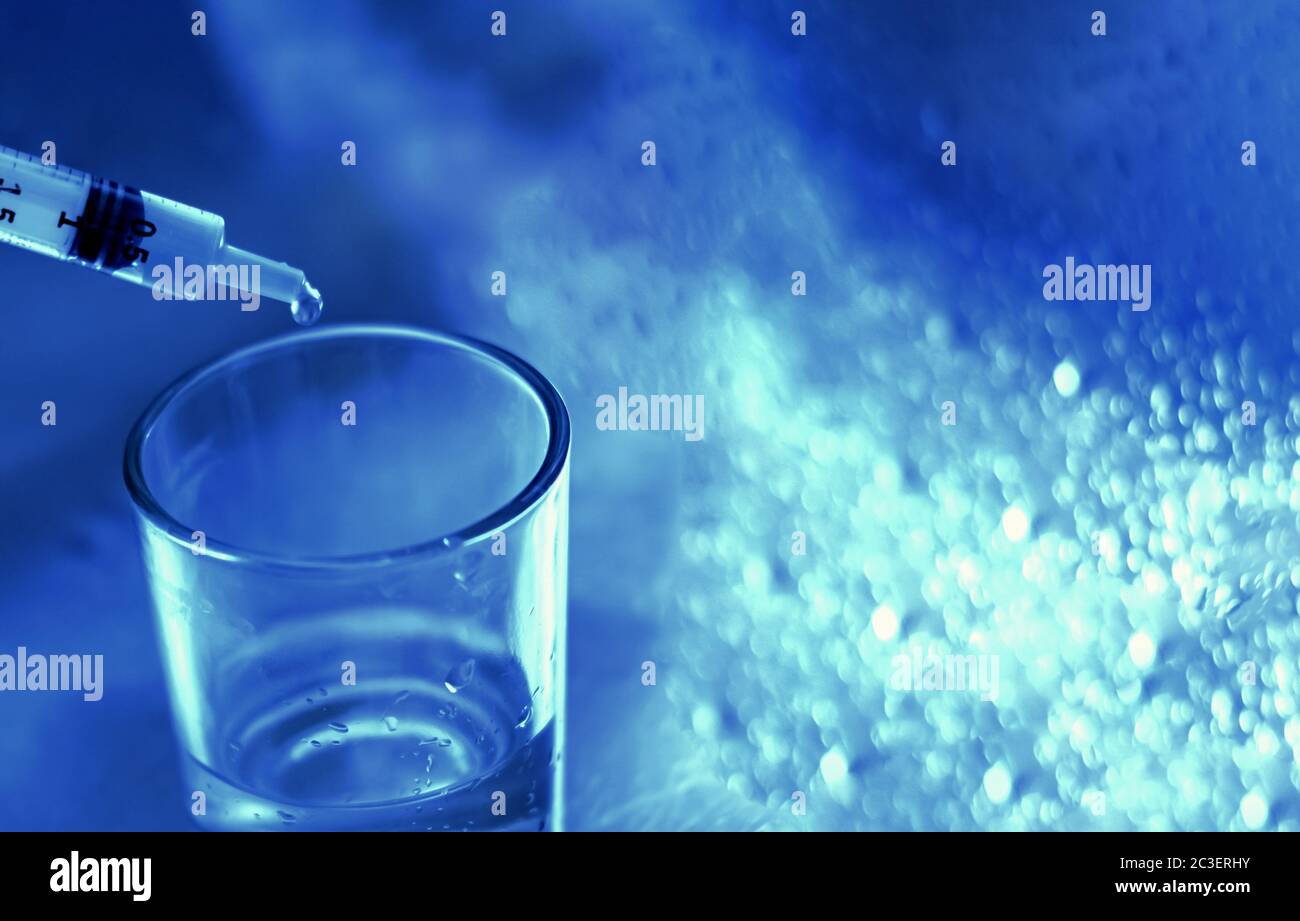 a researcher empties the liquid from a vial into a glass container to