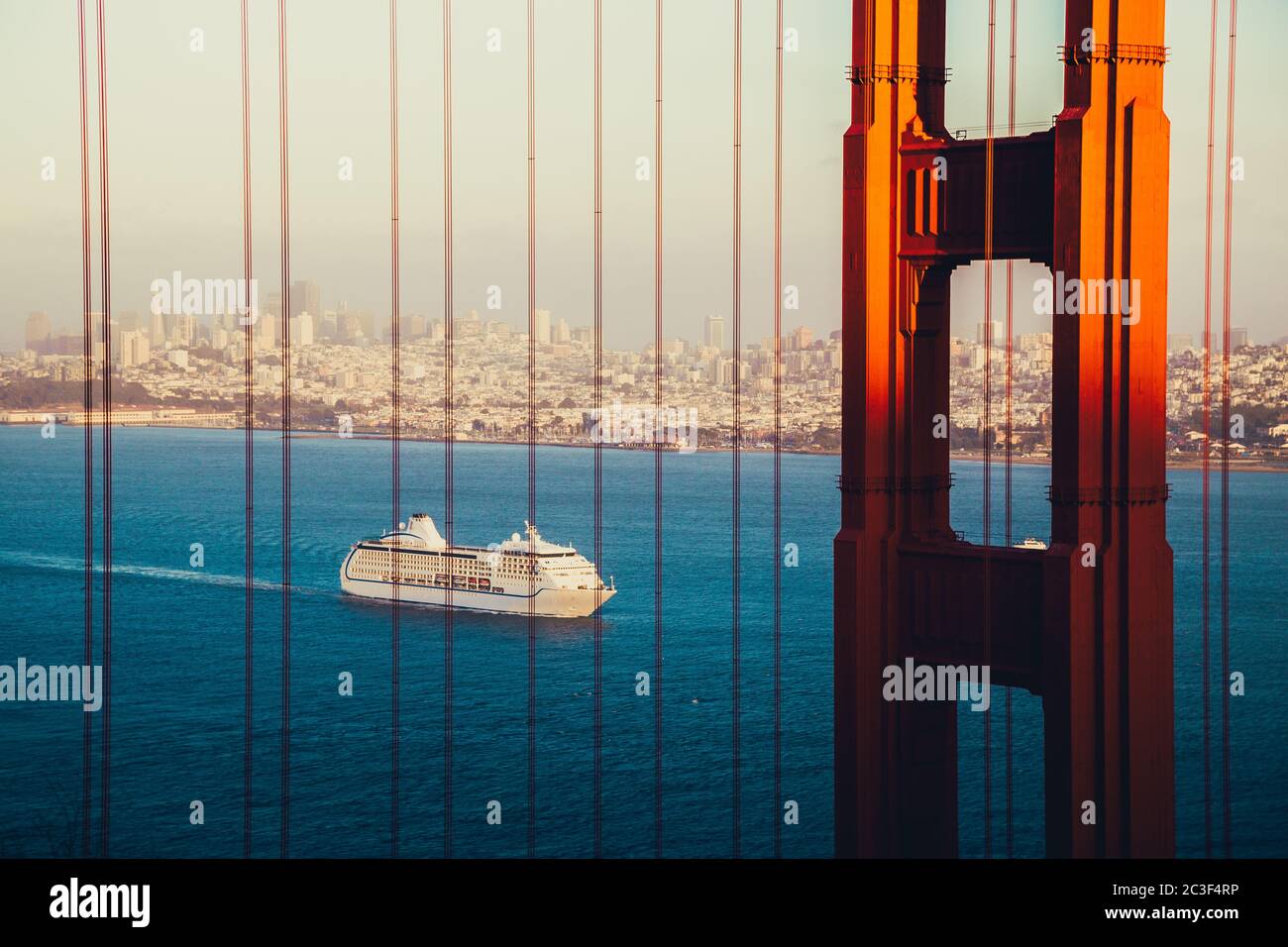 Beautiful panorama view of cruise ship approaching famous Golden Gate Bridge with the skyline of San Francisco in the background at sunset, USA Stock Photo