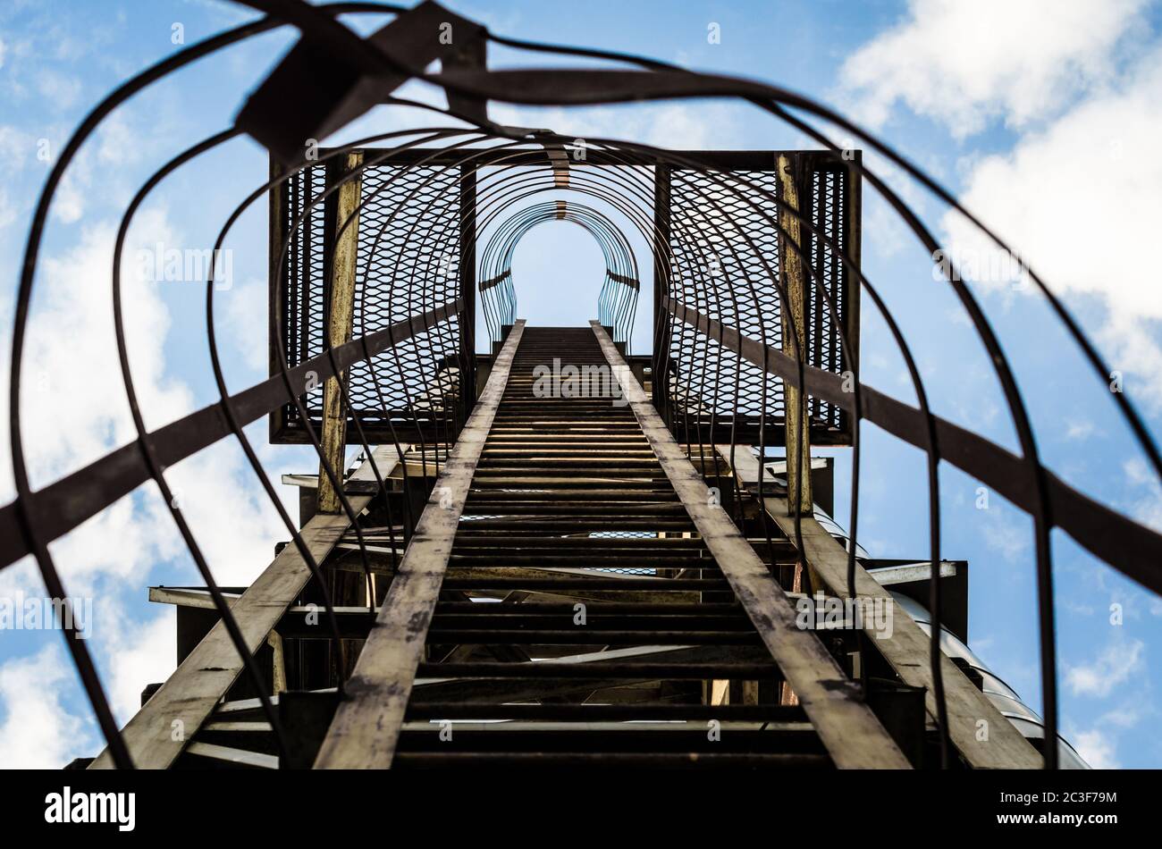 old rusty staircase with damages against the blue sky and clouds Stock Photo