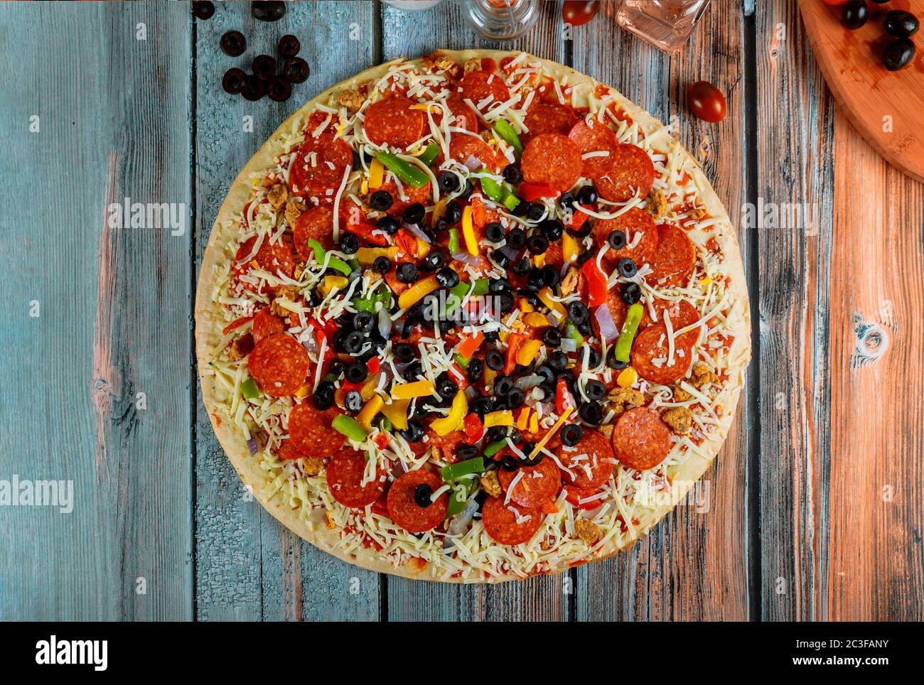 Supreme pizza with olives, oil, cherry tomato on wooden table. Stock Photo