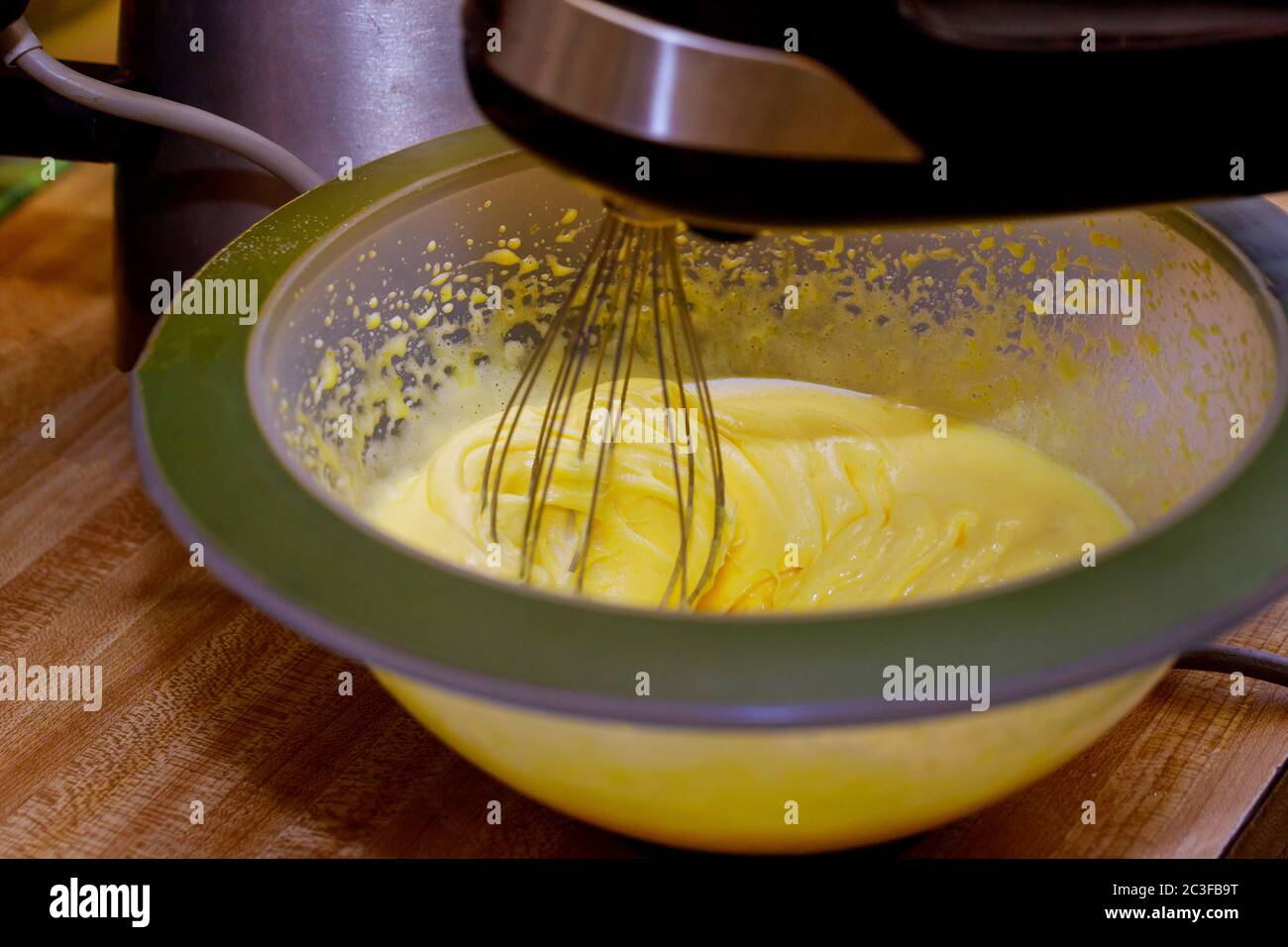 Whipping egg yolks and sugar in bowl with electric mixer Stock Photo