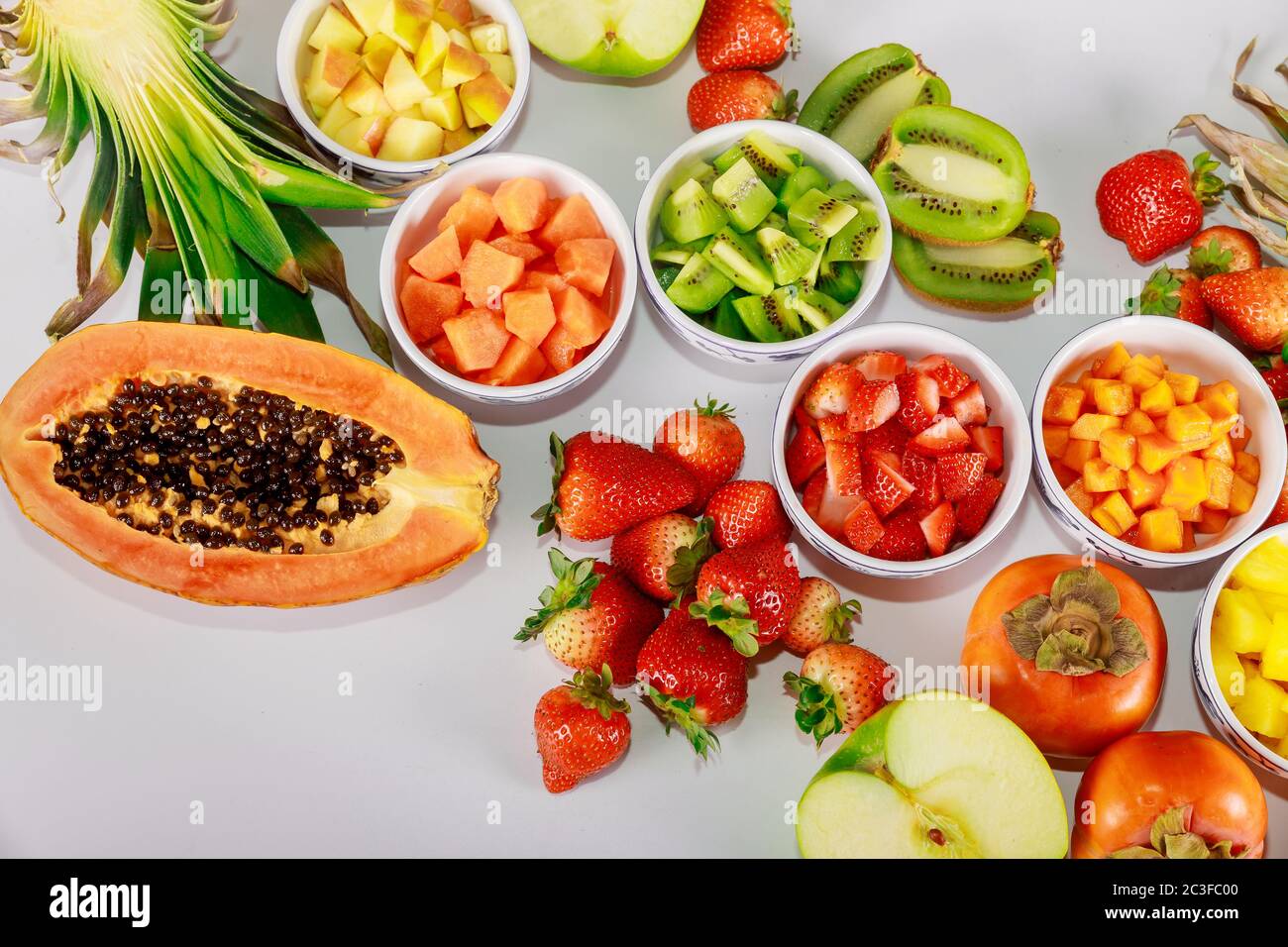 Healthy fruit. Making colorful salad from papaya, strawberry, apple, pineapple, kiwi and persimmon. Stock Photo