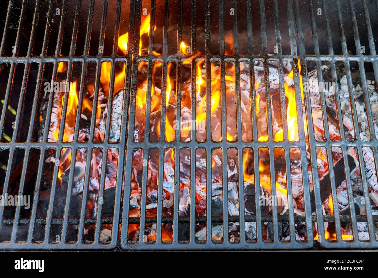 Flames goes through grid of barbecue grill with charcoal Stock Photo