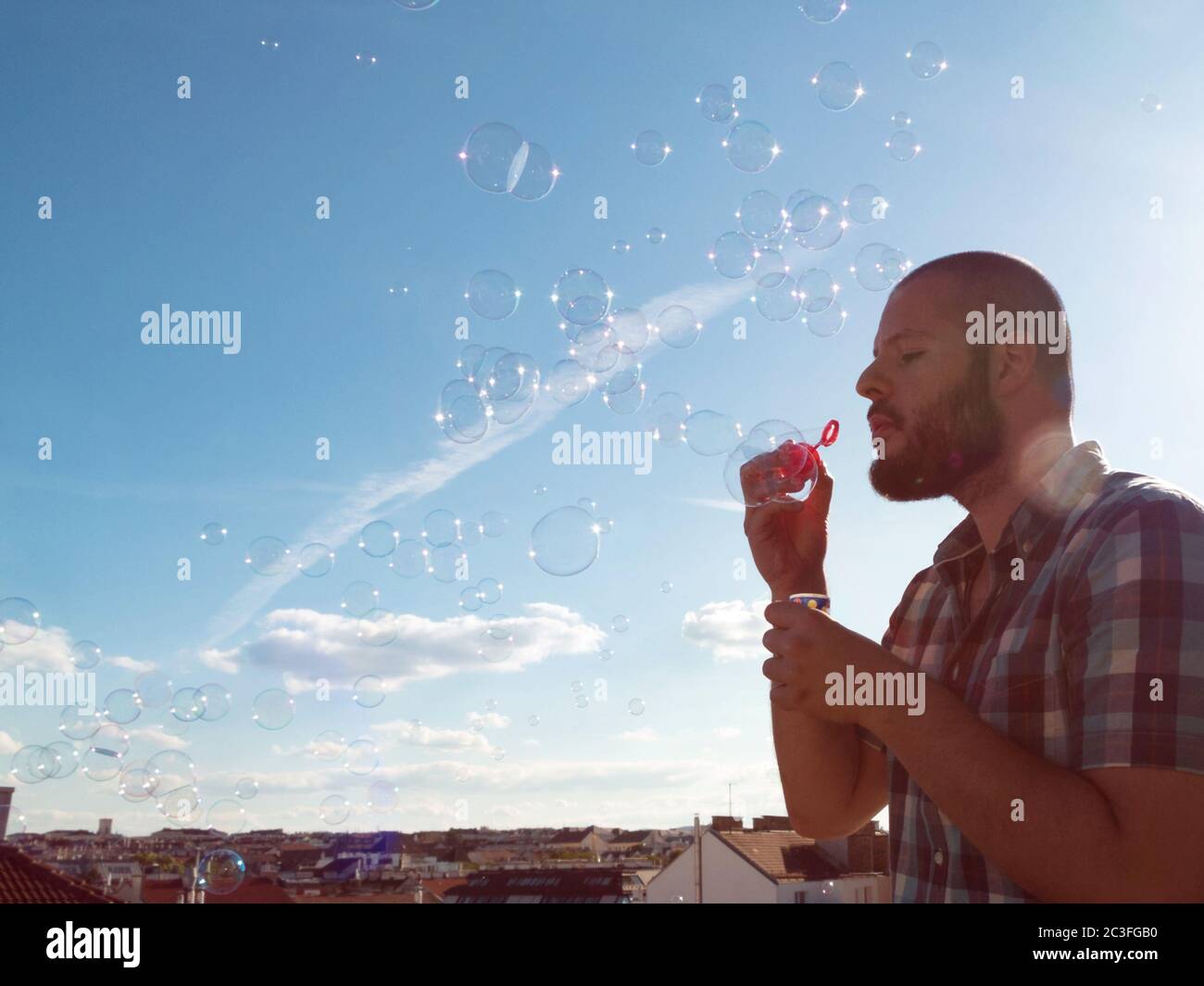 Man blowing soap bubbles from his balcony. Exit restriction quarantine due to coronavirus, home offi Stock Photo