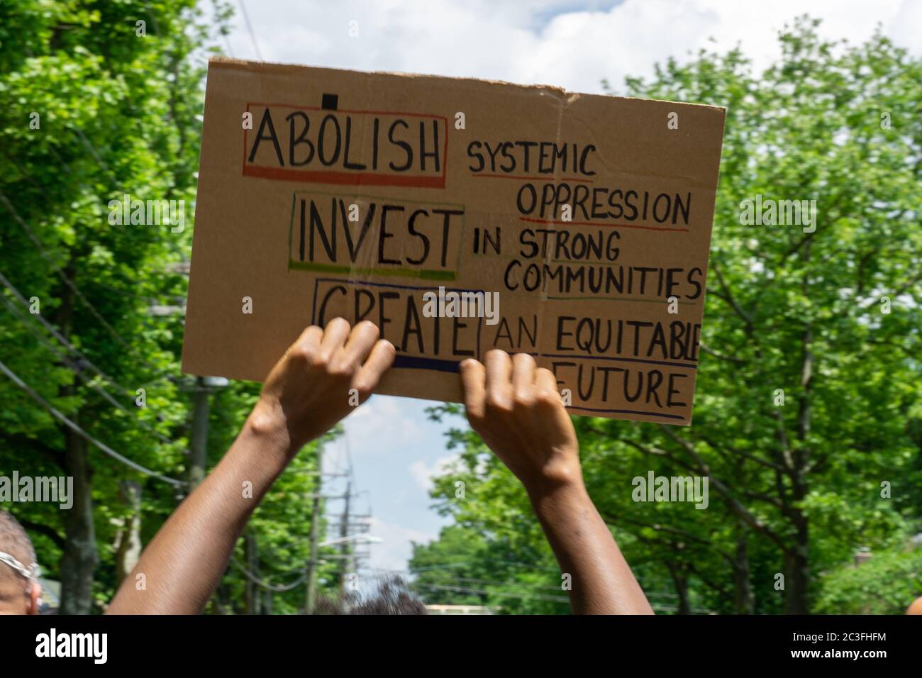 Juneteenth March Black Lives Matter Protest - Black hands holding protest sign up - abolish systemic oppression invest in strong community - create an Stock Photo