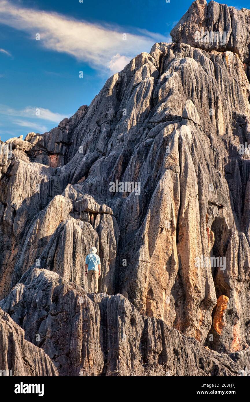 Tourist stands halfway up the limestone ramparts of a cliff face