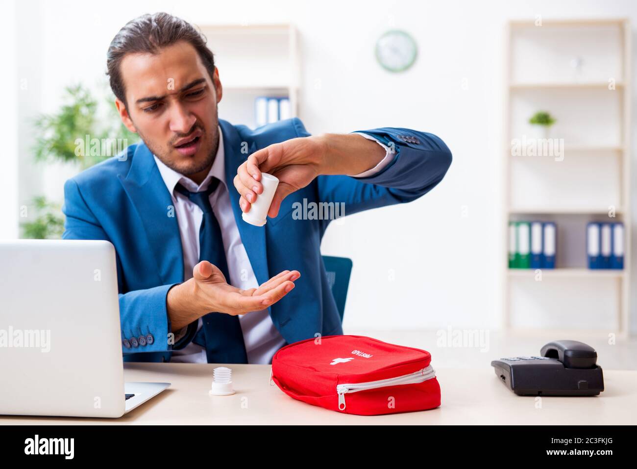Young male employee in first aid concept Stock Photo - Alamy