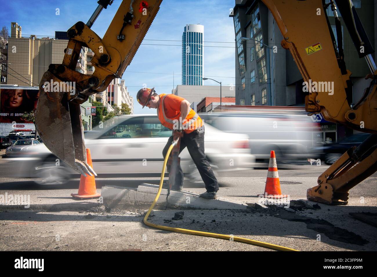 A construction worker uses a jackhammer to break concrete in San Francisco, California Stock Photo
