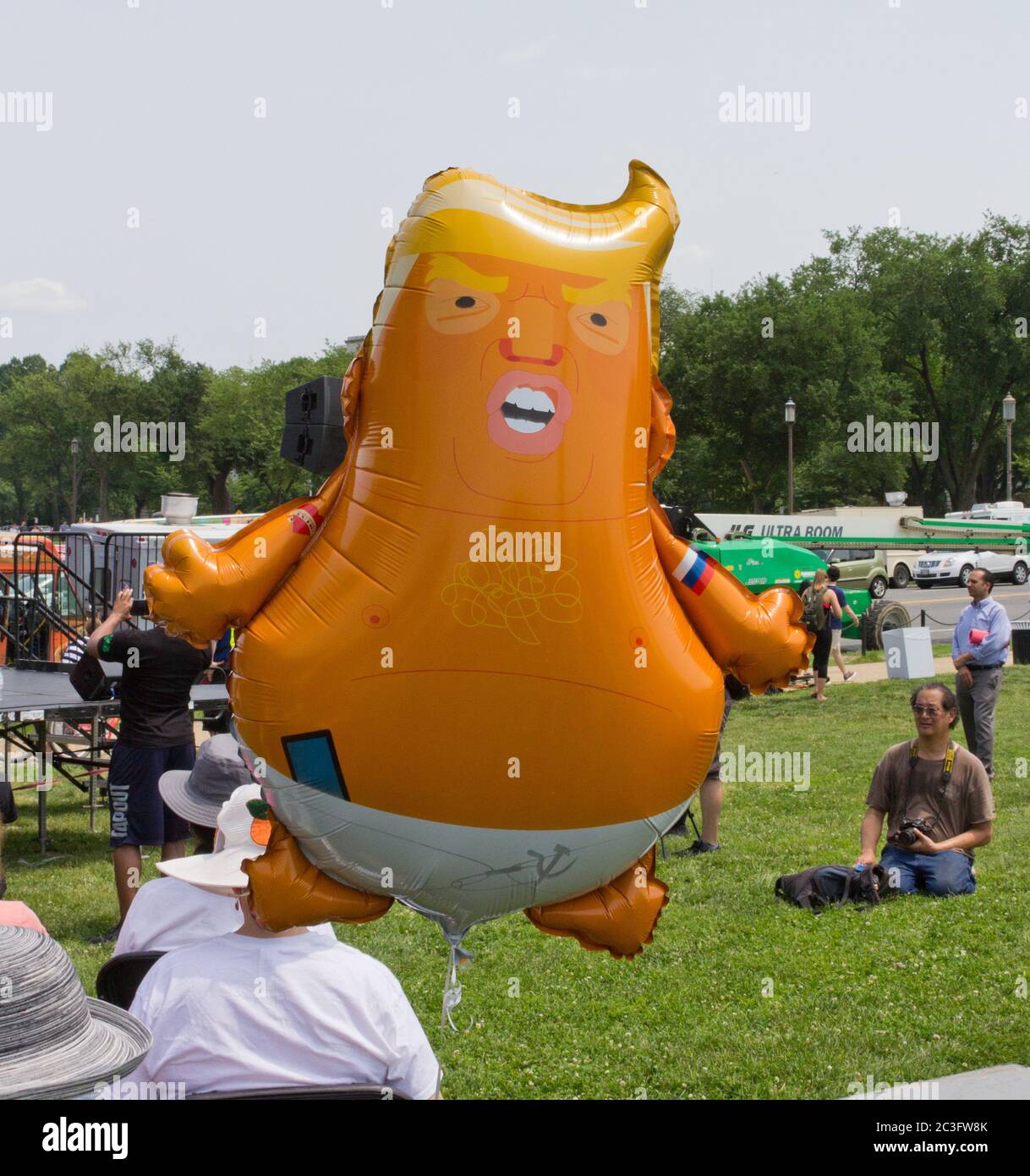 Washington, D.C., USA. 1st June, 2019. Protester's helium balloon depicting a cartoon version of President Donald J. Trump as a baby in diapers with a Russian hammer and sickle emblem on his diaper pin, and a Putin heart tattoo and the tricolors of the Russian flag on his arms, floats above the brimmed hats on participants' heads at the National March To Impeach; a man with a camera around his neck in the background. Organized by the group People Demand Action, the demonstration on the Washington Monument Grounds called for the United States Congress to initiate impeachment. Kay Howell/Alamy Stock Photo