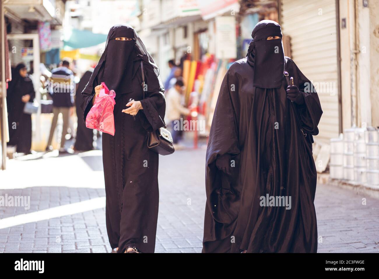 Manama / Bahrain - January 10, 2020: Muslim women wearing traditional black abaya niqab while shopping in Manama Souq, also a famous tourist destination in the capital of Bahrain Stock Photo