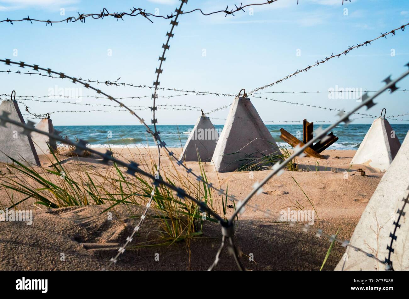 barbed wire and concrete military fence on the beach near the sea in Crimea Stock Photo