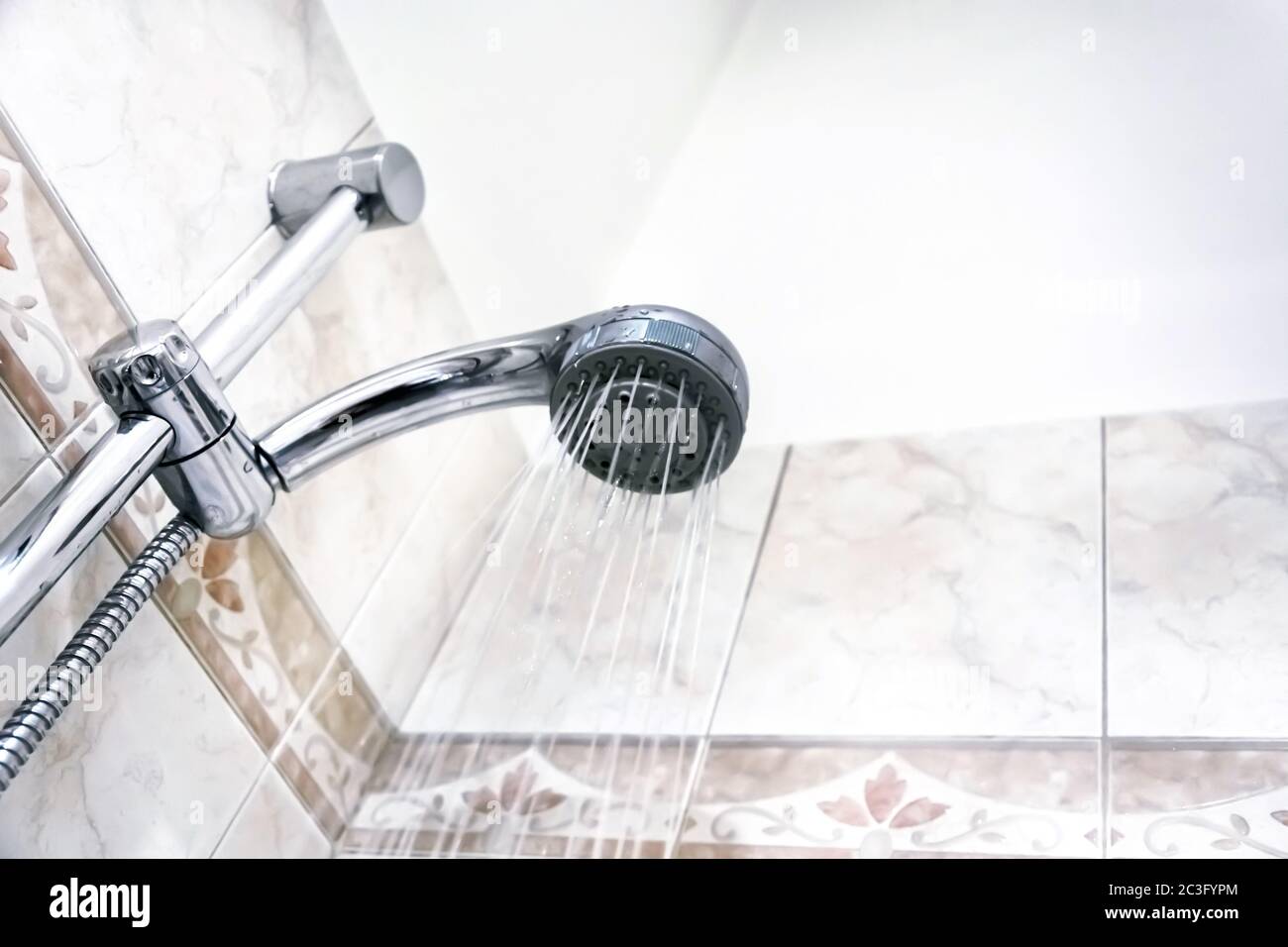 Interior of a shower with water flowing from the shower head. Droplets
