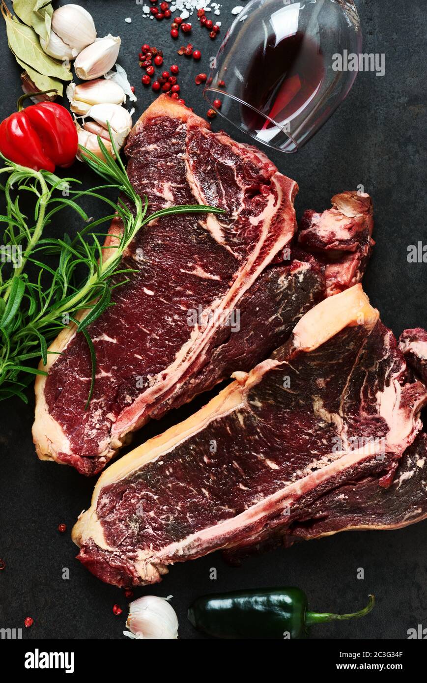 Raw aged steak and seasoning on dark background Stock Photo