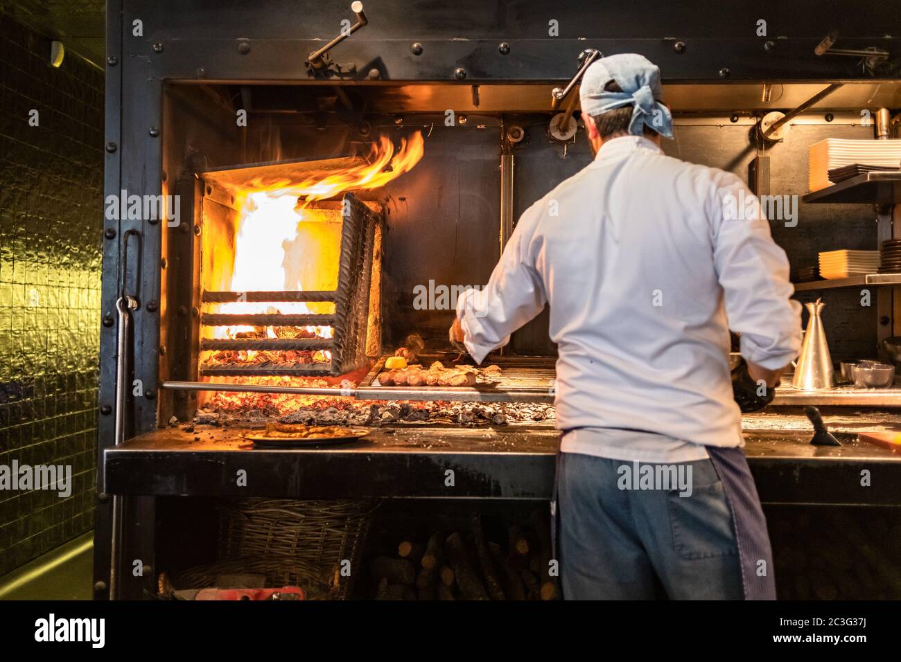 Chef cooking meat and sausages on grill. Focus on meat. Stock Photo