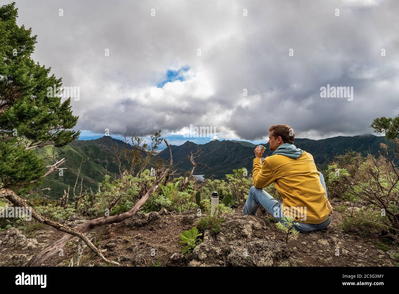 Young male traveler drinks a hot drink in the mountains. tea or coffee from thermos in the nature Stock Photo - Alamy