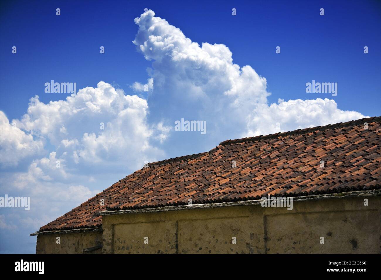 Low angle shot of old roof tiles of a building with a cloudy blue sky in the background Stock Photo