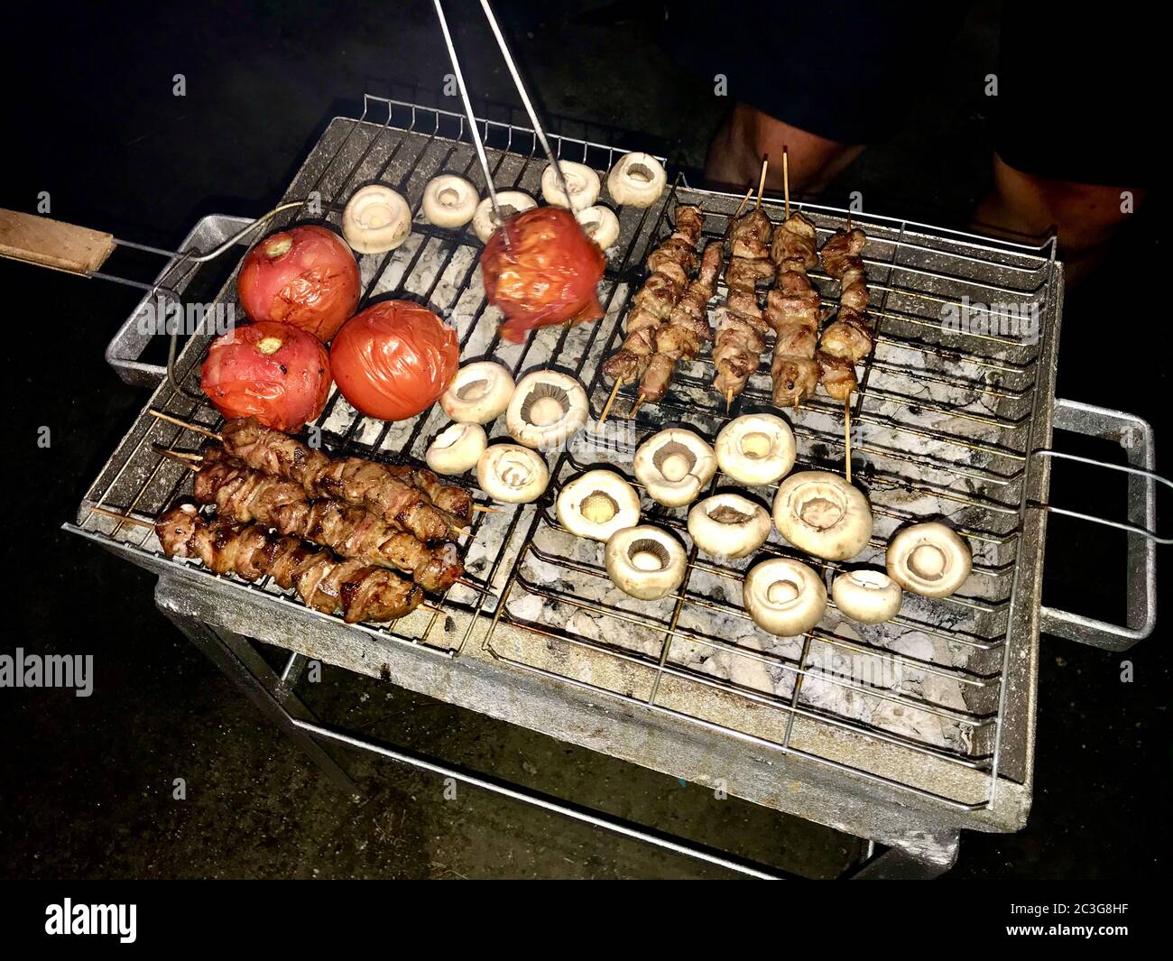 Turkish Style Lamb Kebab Shish Skewer Cooked with Mushrooms and Roasted Tomatoes on Street Barbecue Mangal. Traditional Cooking. Stock Photo