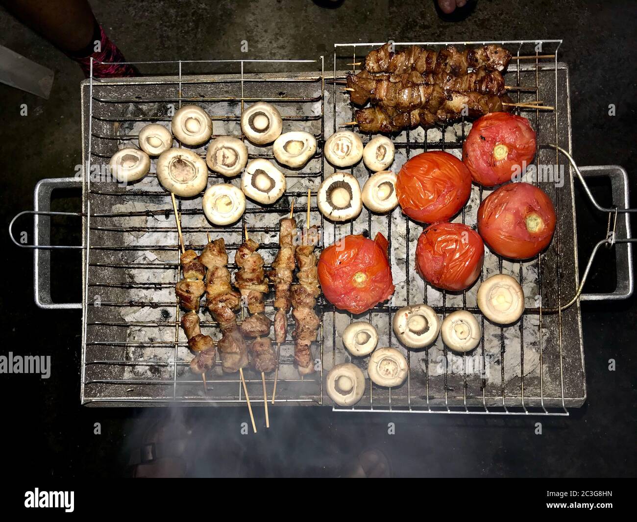 Turkish Style Lamb Kebab Shish Skewer Cooked with Mushrooms and Roasted Tomatoes on Street Barbecue Mangal. Traditional Cooking. Stock Photo